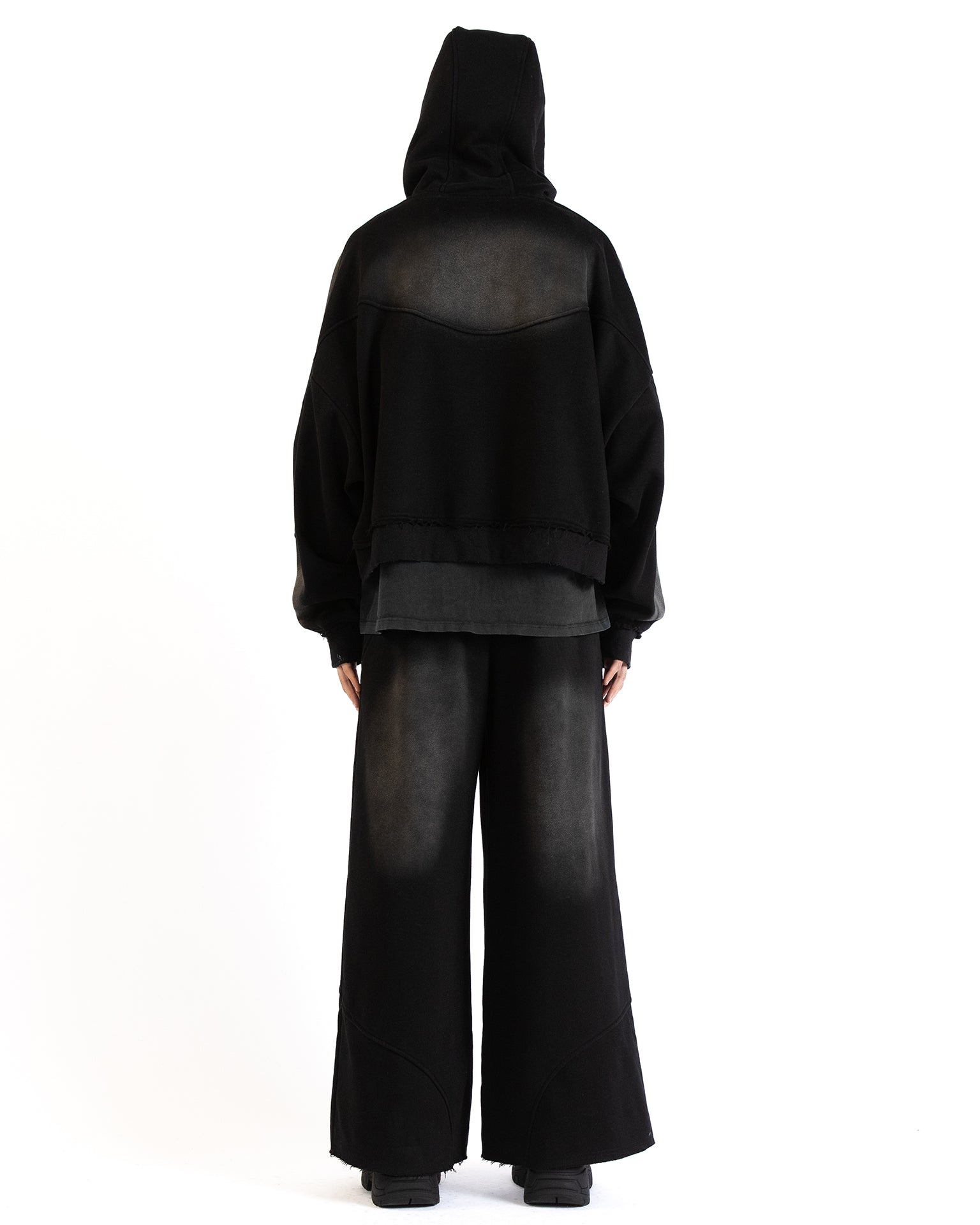 Back view of the Untitled Artworks Consumed Hoodie in black, showcasing its oversized fit, kangaroo pocket, and unique stone wash effect.