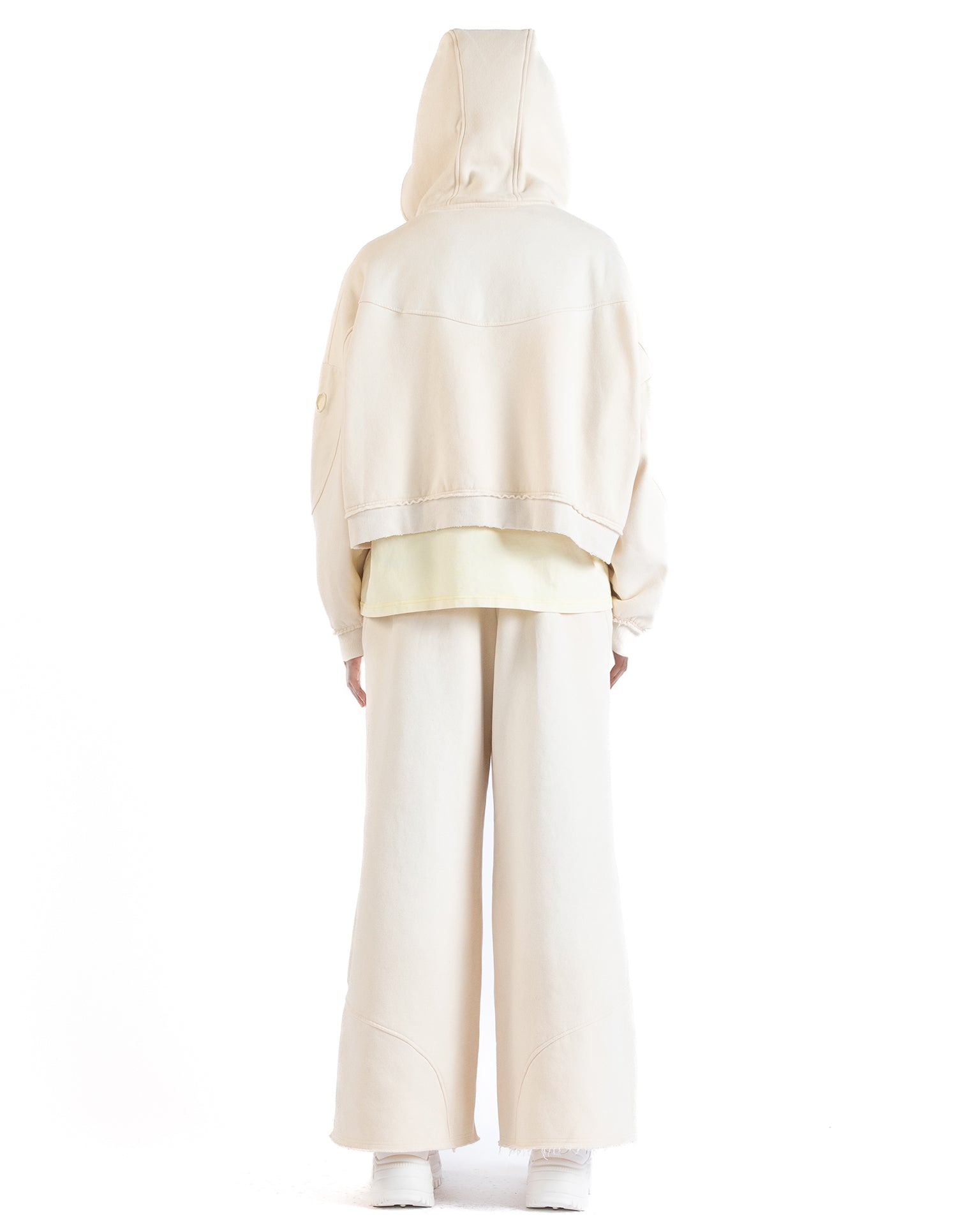 Back view of the Untitled Artworks Consumed Hoodie in cream, showcasing its oversized fit, kangaroo pocket, and unique stone wash effect.