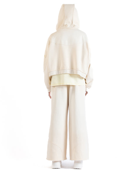 Back view of the Untitled Artworks Consumed Hoodie in cream, showcasing its oversized fit, kangaroo pocket, and unique stone wash effect.
