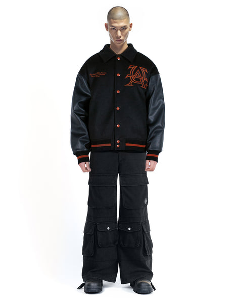 Untitled Artworks “Cult” varsity jacket in black with oversized fit and letterman-style embroidered graphics. front on model