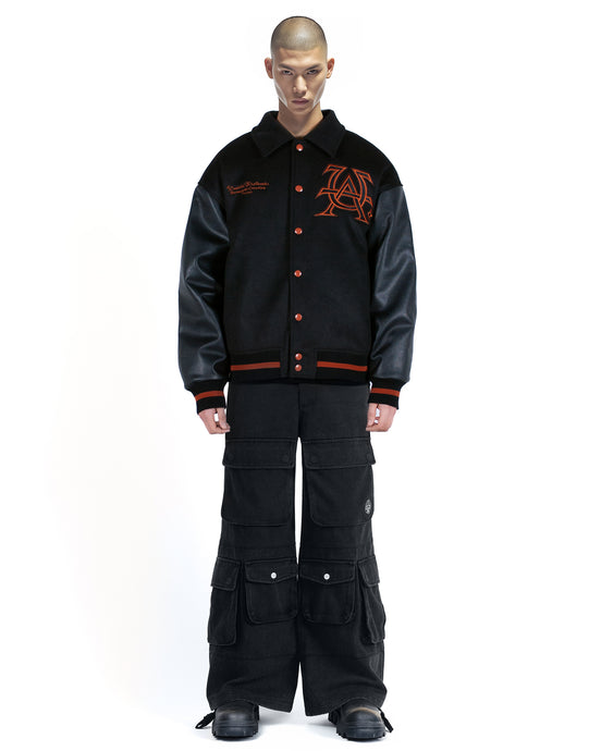 Untitled Artworks “Cult” varsity jacket in black with oversized fit and letterman-style embroidered graphics. front on model