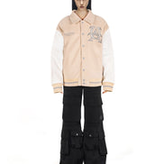 Untitled Artworks “Hunting Oat” varsity jacket in tan (oat) with embroidered hunting graphics and oversized letterman fit. on model front 