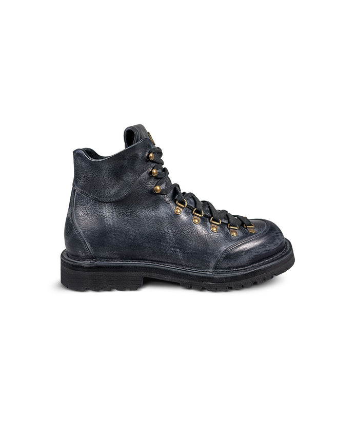 Close-up side view of the Untitled Artworks x Fracap Destroyer Boot in black, showcasing its spray-effect finish, oversized fold-over tongue, and antique brass eyelets.