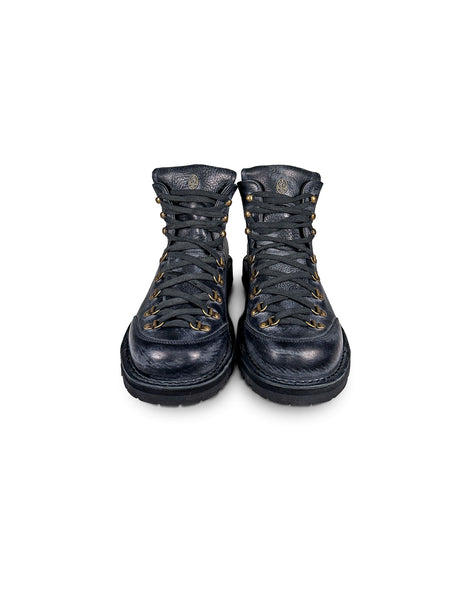 Close-up front view of the Untitled Artworks x Fracap Destroyer Boot in black, showcasing its spray-effect finish, oversized fold-over tongue, and antique brass eyelets.
