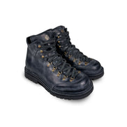 Close-up 3/4 view of the Untitled Artworks x Fracap Destroyer Boot in black, showcasing its spray-effect finish, oversized fold-over tongue, and antique brass eyelets.