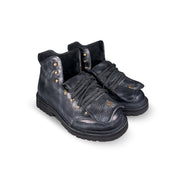 Close-up 3/4 tongue down view of the Untitled Artworks x Fracap Destroyer Boot in black, showcasing its spray-effect finish, oversized fold-over tongue, and antique brass eyelets.